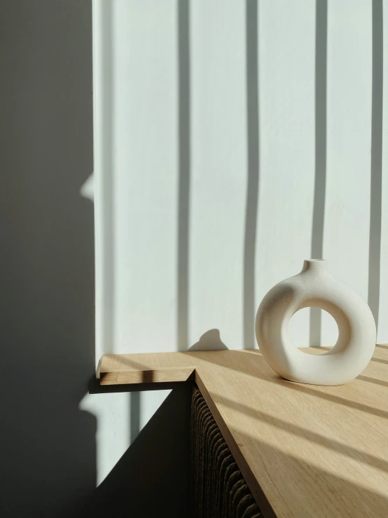 an empty vase sitting on a table by the wall
