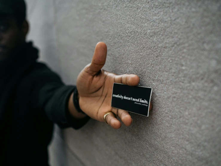 a person in a black jacket holding up a business card