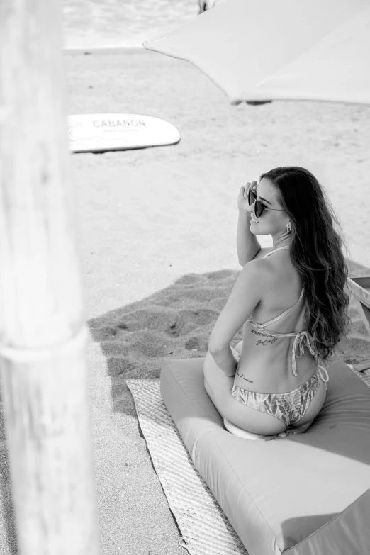 a black and white pograph of a woman on the beach in a bikini