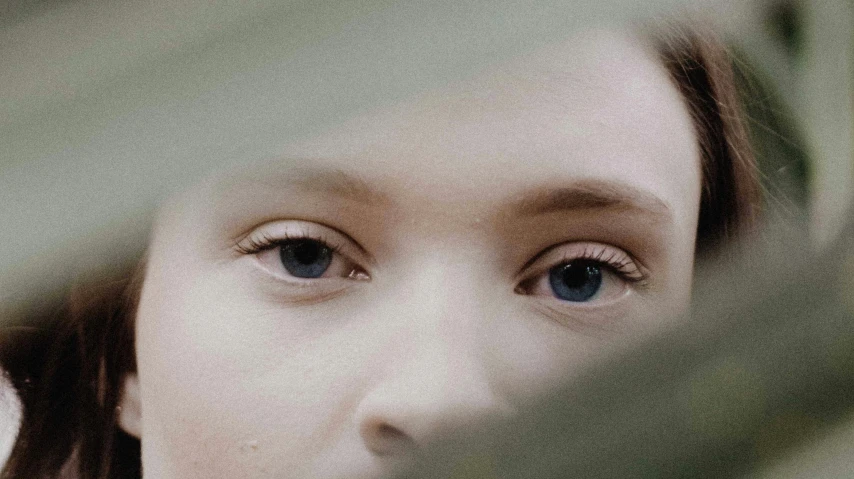 a girl is looking into the camera through a window