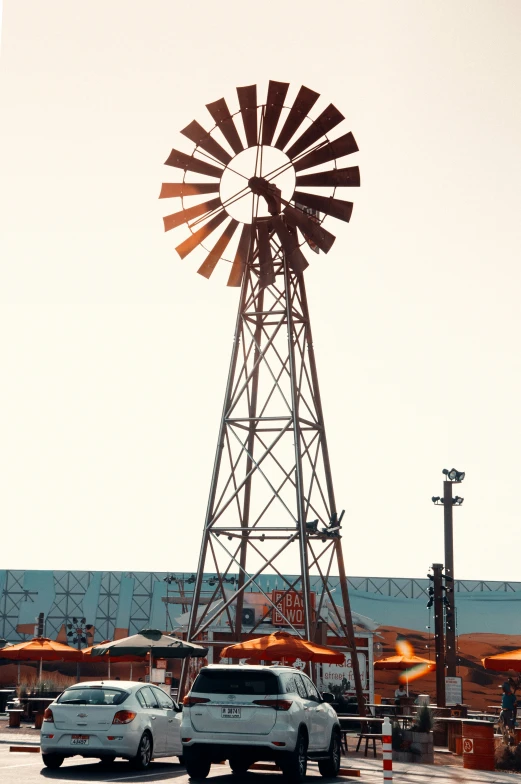 cars driving past a tall windmill near a street