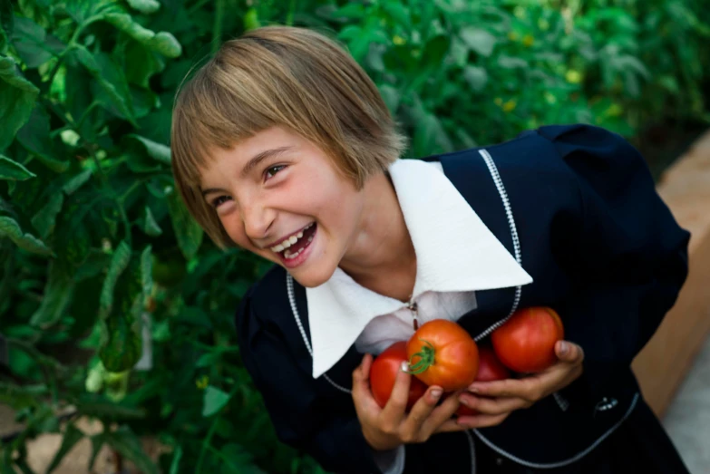 a boy holds a bunch of tomatoes in his hands