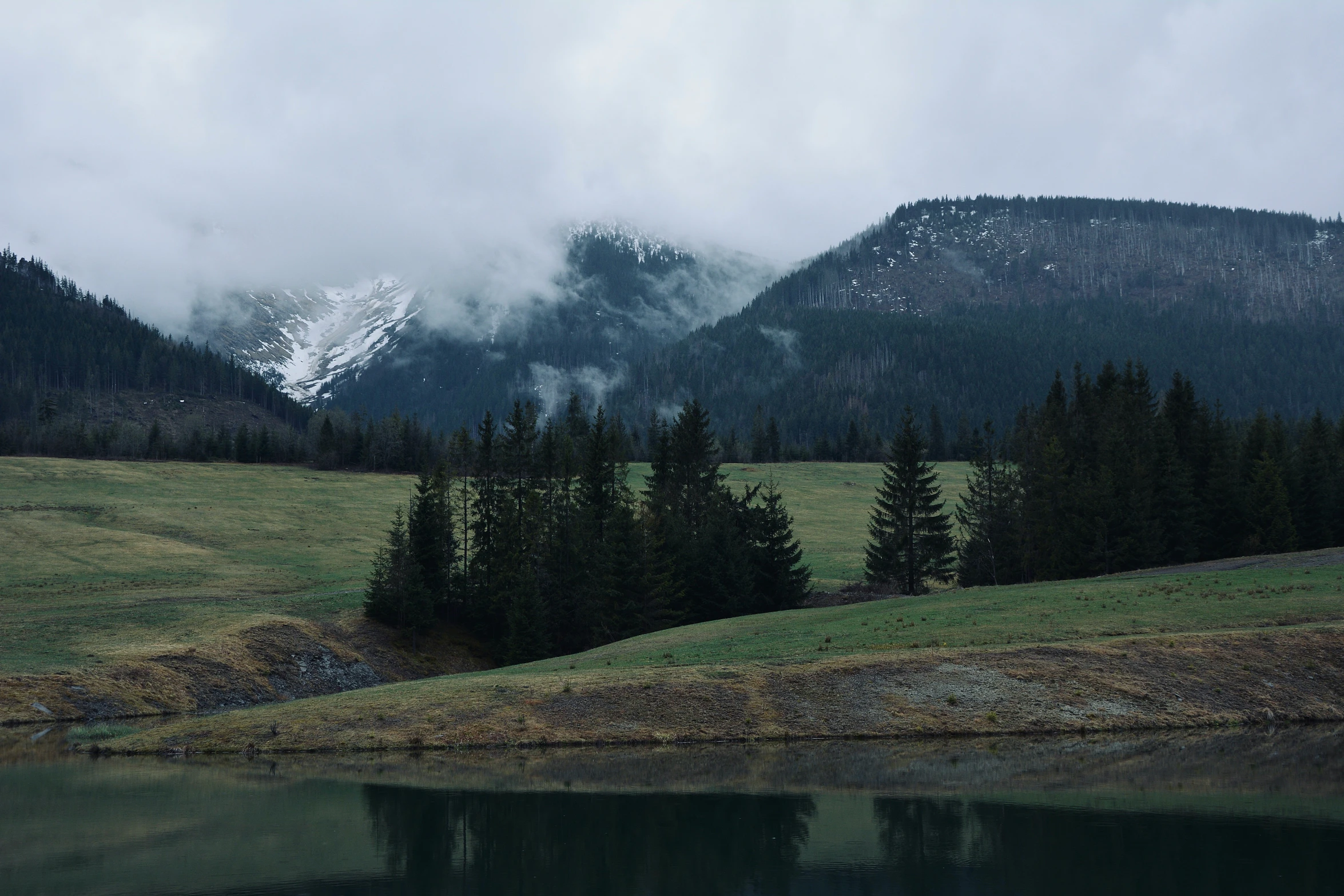 a couple of mountains sit in the distance with mist