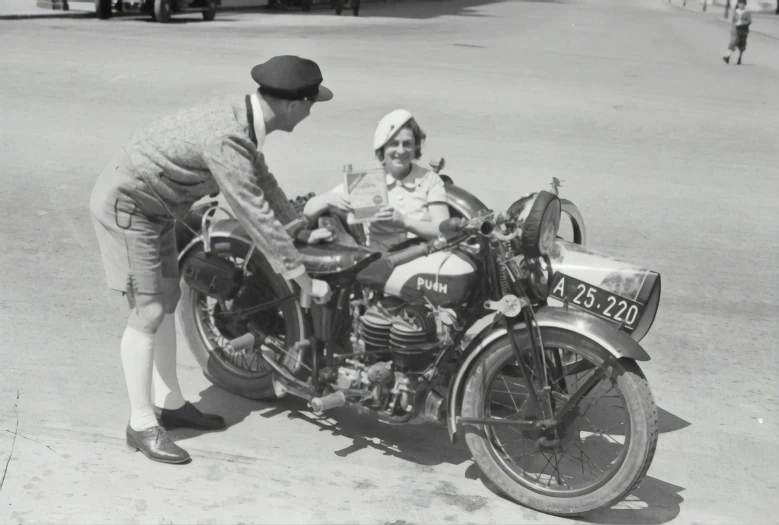 two people sit on an old motorcycle and look at it