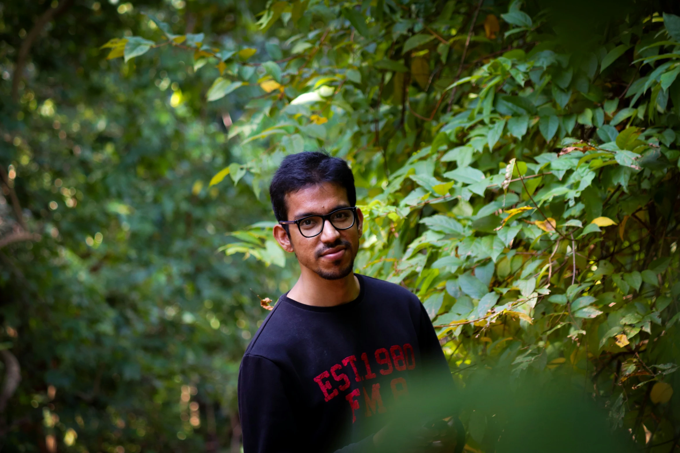 a man is looking off to the side while wearing a black sweatshirt with red letters