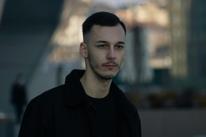 a man is looking at the camera while standing near buildings