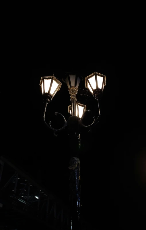 two street lamps lit up at night on a pole