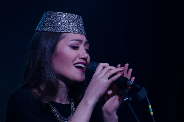 a woman singing into a microphone wearing a crown