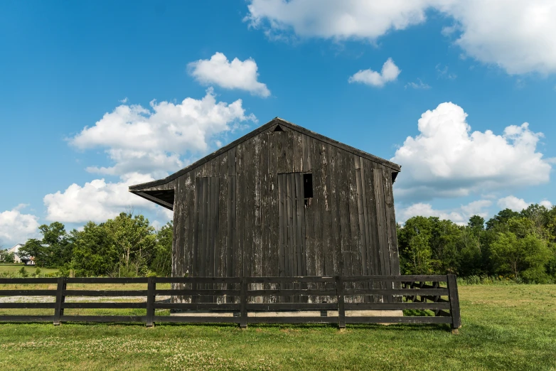 an old barn with a wooden fence on the grass