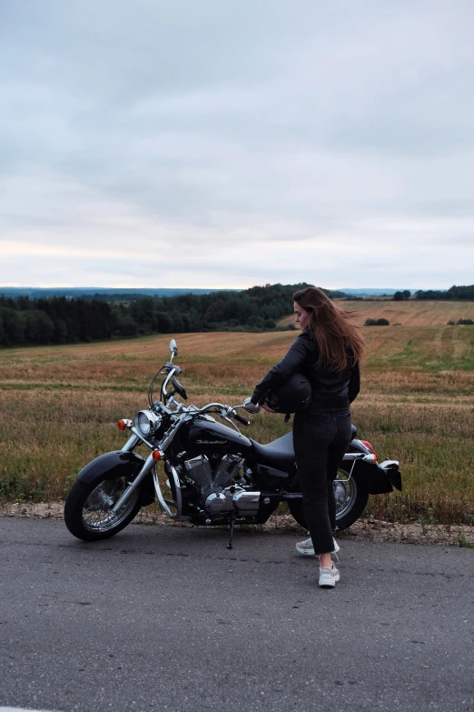 a woman standing in front of a motorcycle