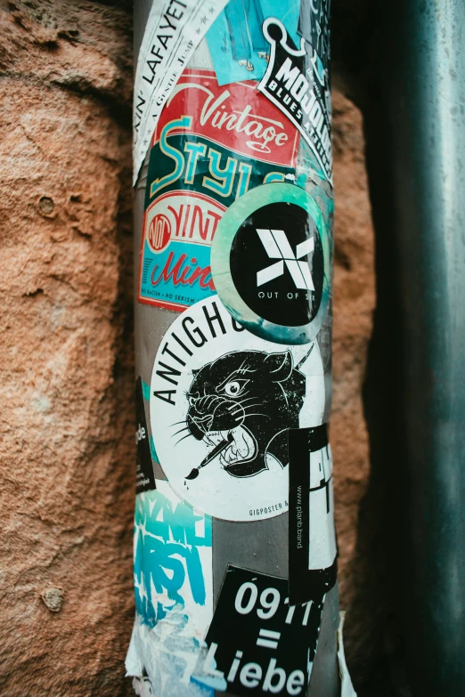 stickers are shown on a pole along side a wall