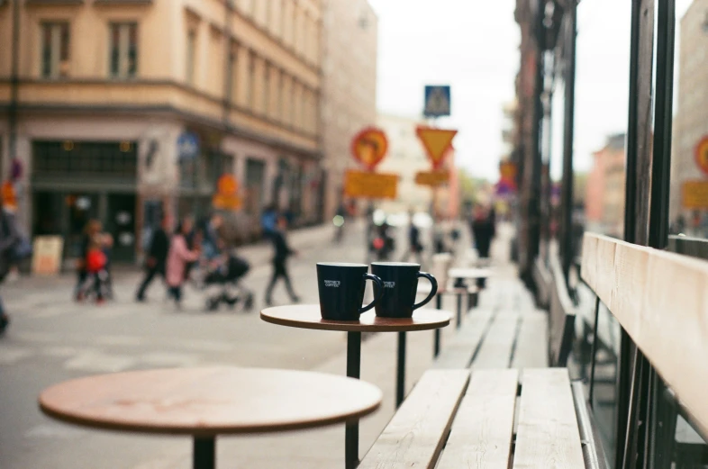 two coffee cups are set on top of a table outside