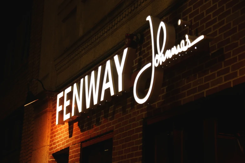 an illuminated sign on the side of a brick building