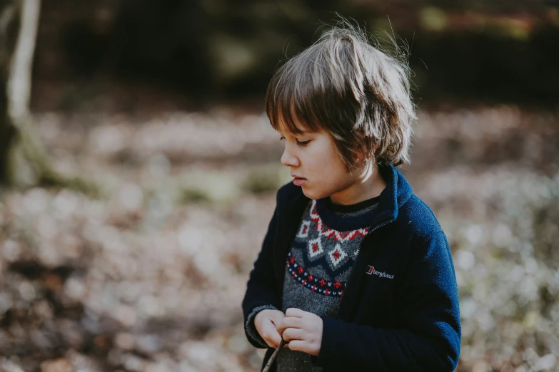 a little boy standing in a forest holding an umbrella