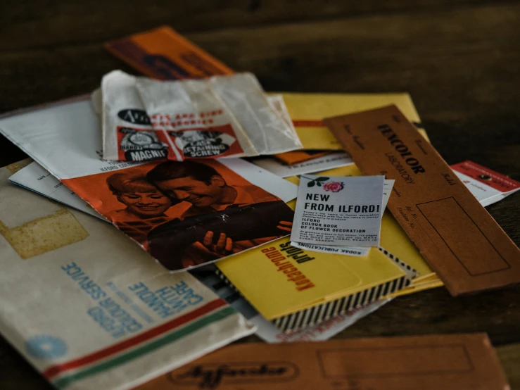 a pile of mail that are on top of a wooden table