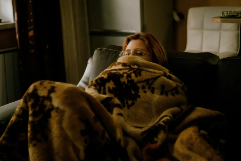 the woman wrapped in the blankets is sleeping on the couch