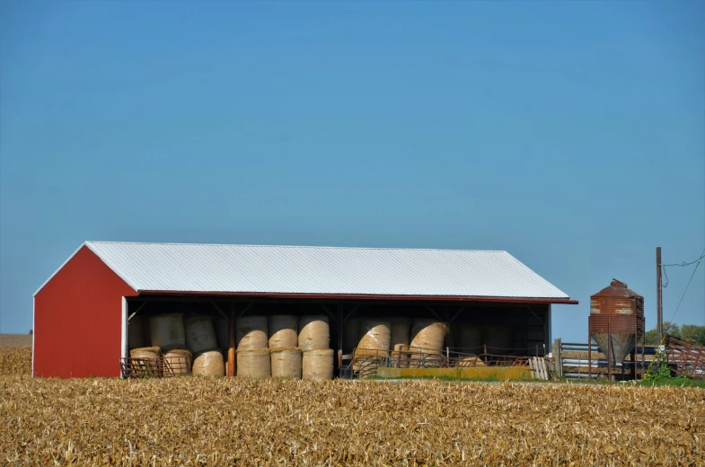 an empty barn with large tanks next to a grain field