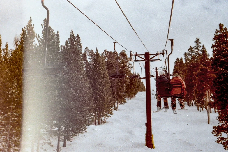 two people ride down the ski lift in the snow