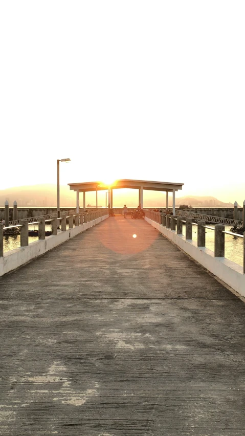 the sun is setting at the dock by some water