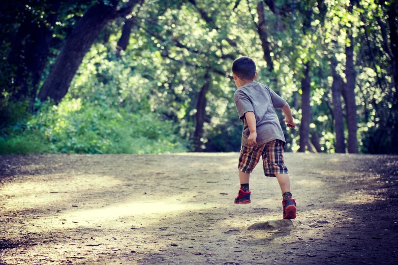 a small boy playing soccer in a forest