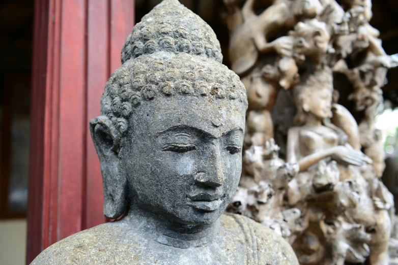 statue of buddha in front of a sculpture of a woman and three other tree nches