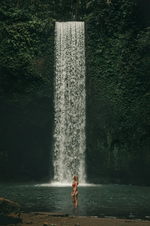 a young man standing in front of a waterfall