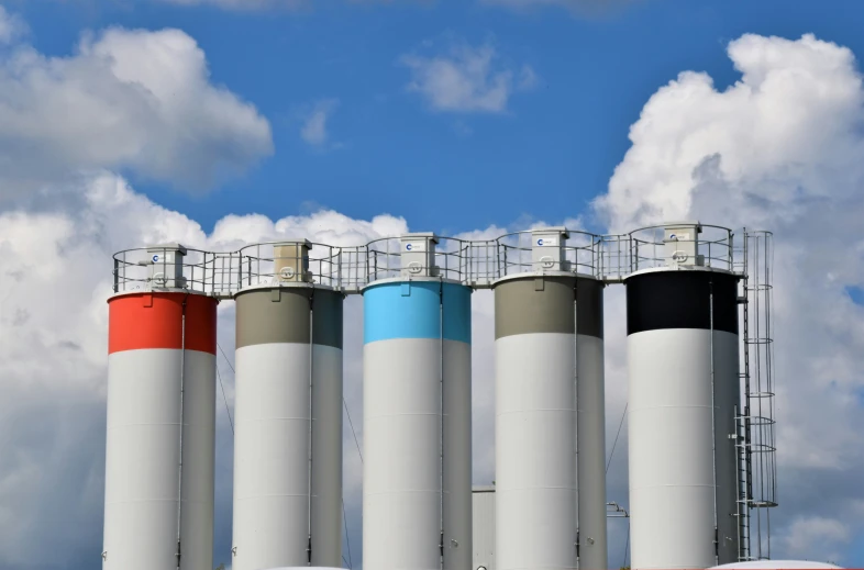 several silos with colorful accents and blue skies behind them