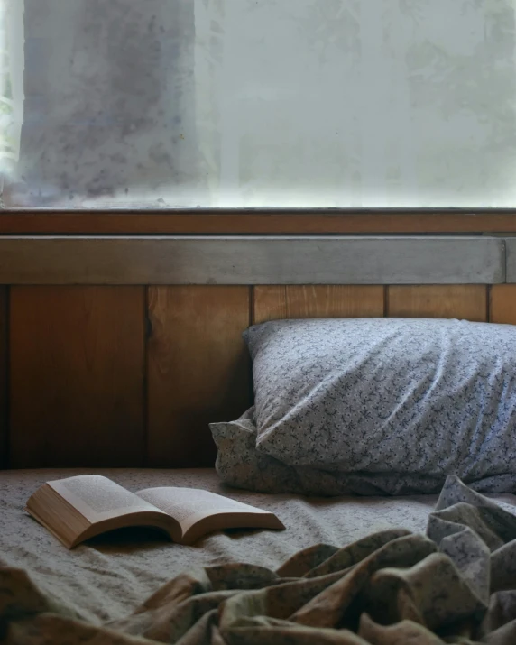 an open book laying on a bed under a window