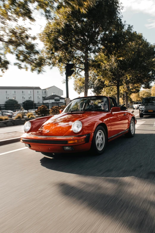 a red porsche sports car driving down a street