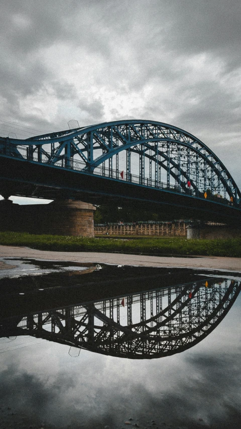 a bridge in the background is reflected in the water