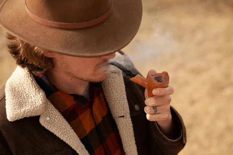 man in brown hat smoking with pipe and wearing jacket