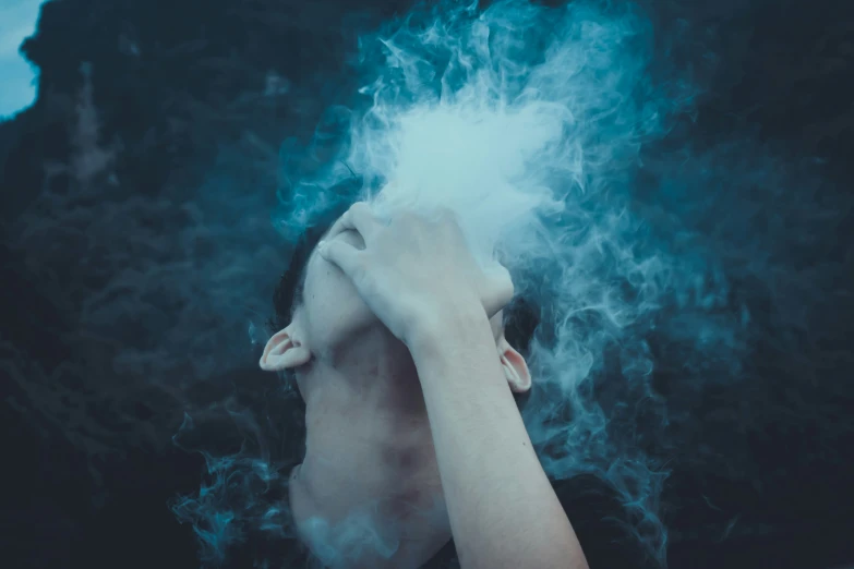 woman in black dress holding her head close to smoke