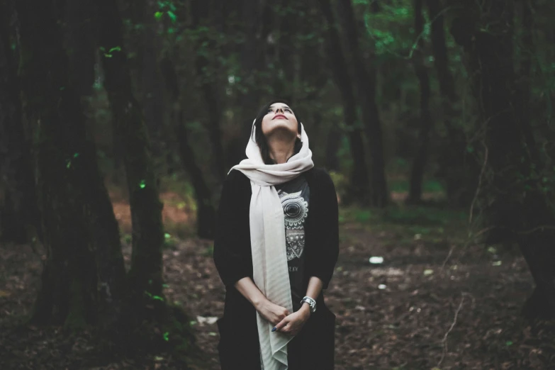 a woman standing in the forest while looking up