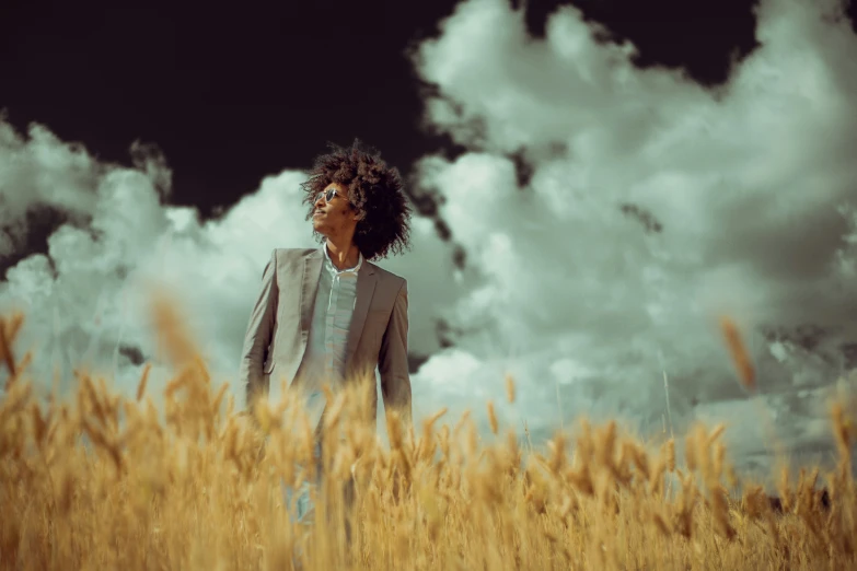 the man in the coat is standing in a field of wheat