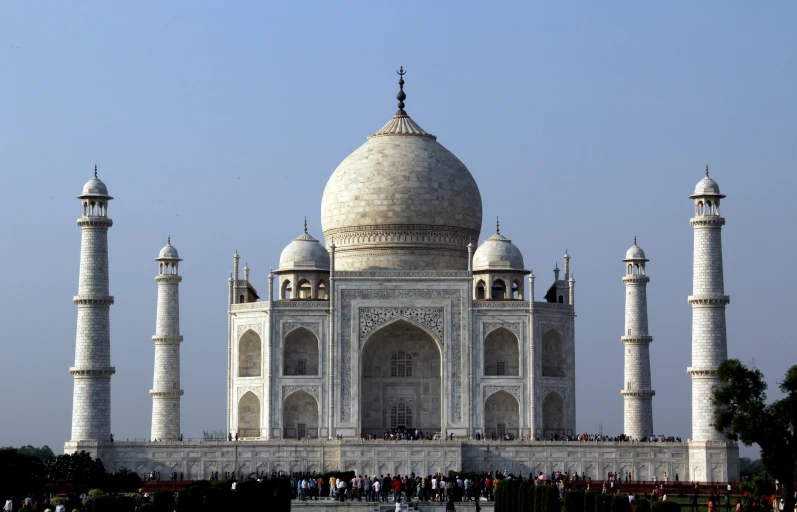 the taj, a large white - stone monument, in front of a blue sky