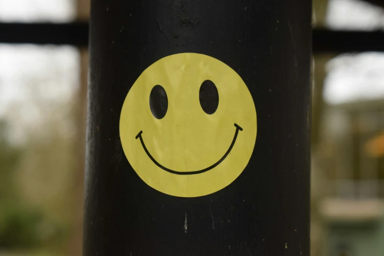 there is a yellow smiley face painted on the back of the pole