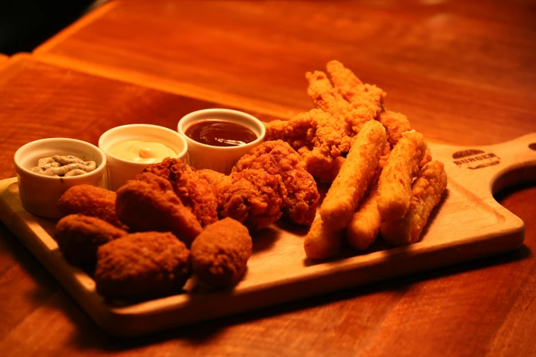 fried food items on wooden serving board with dipping sauce