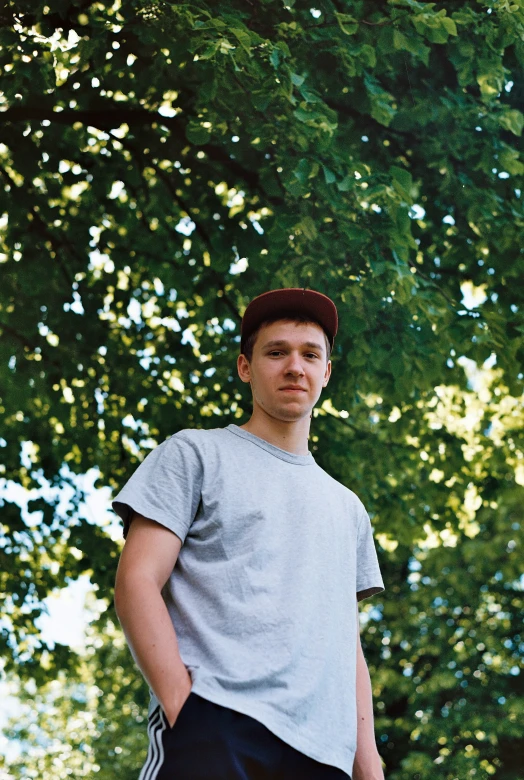 a boy posing for the camera in front of trees