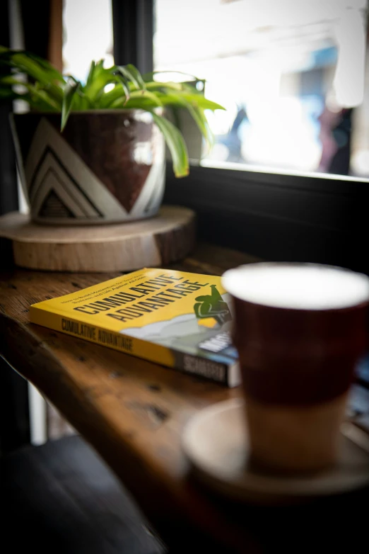 a coffee cup and a small yellow book sit on a table