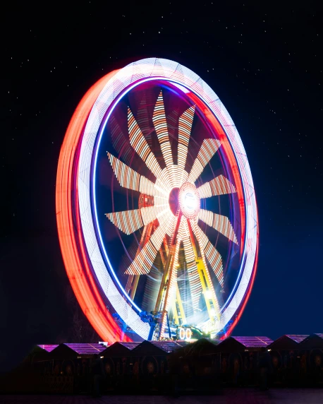 a ferris wheel lit up at night with a bright light show