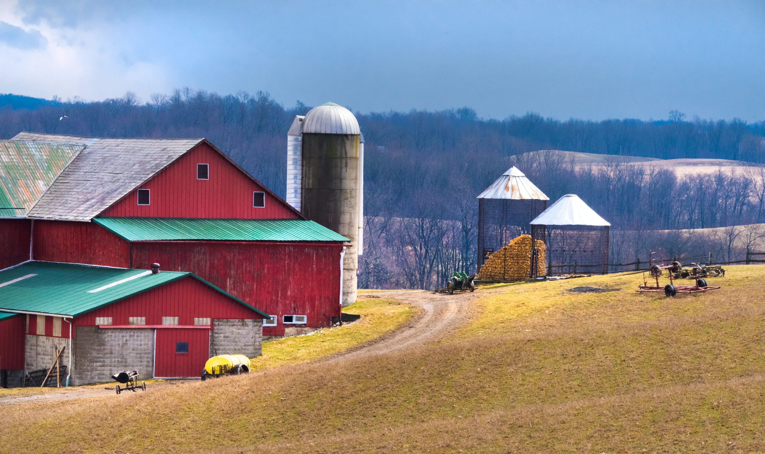 a field with a farm, silos and a large barn