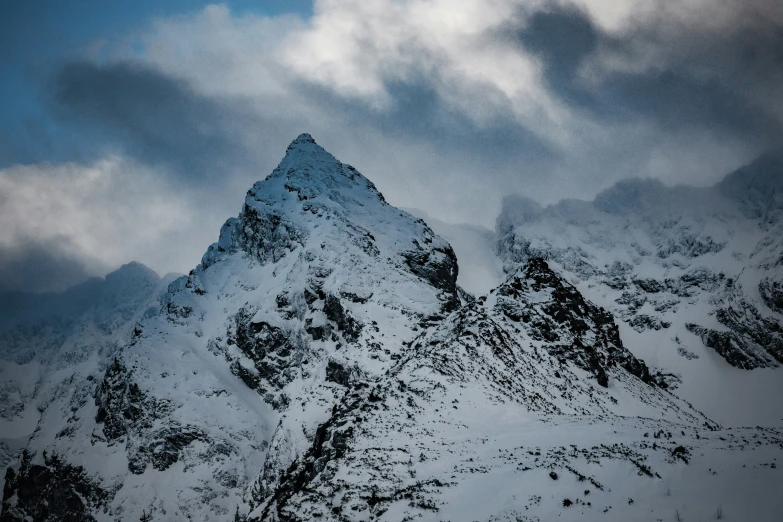 a snowy mountain peak with dark clouds in the background