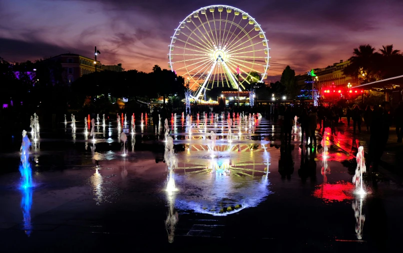 a ferris wheel is shining brightly on the dark night