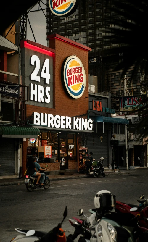 a burger king and two men on motorcycles at night