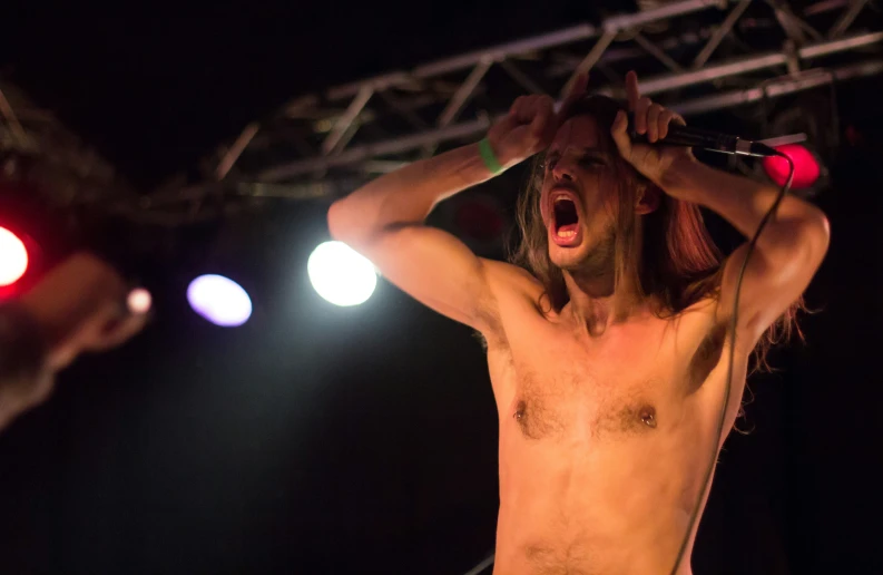 a shirtless man is holding his hair in the air