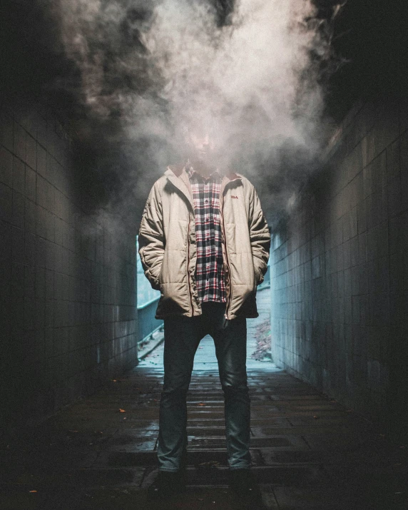 man standing in the end of a dark tunnel with smoke coming out