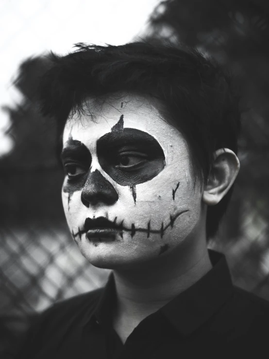 a young man with halloween makeup is wearing a fake skeleton face