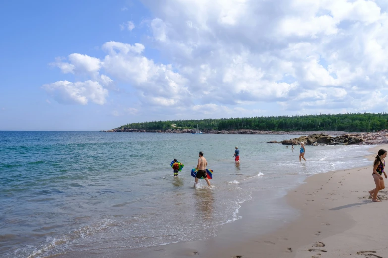 several people walk through the water on a beach