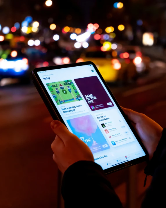 a person holding an electronic device displaying a street at night