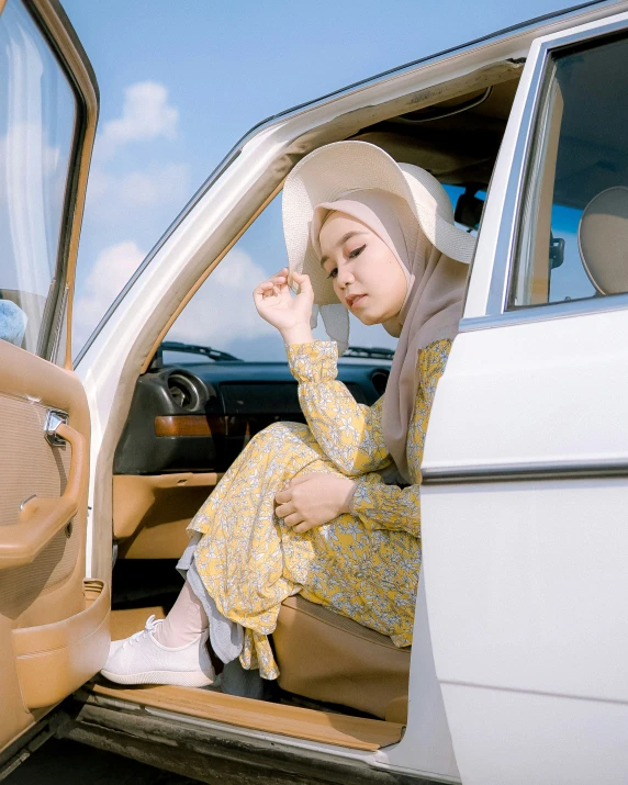 a woman sitting on the seat of a car while wearing a hat